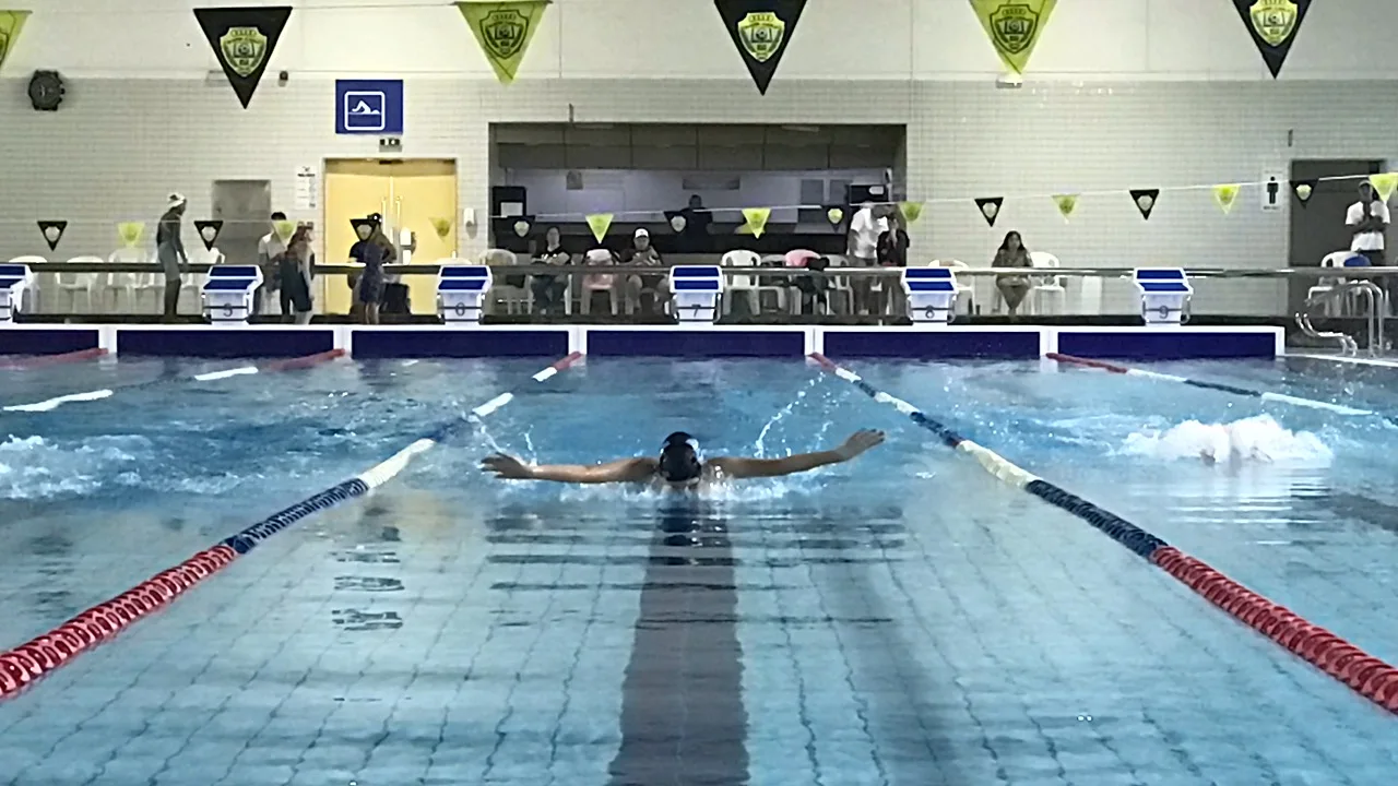 A swimmer powering through butterfly in a Dubai competition pool